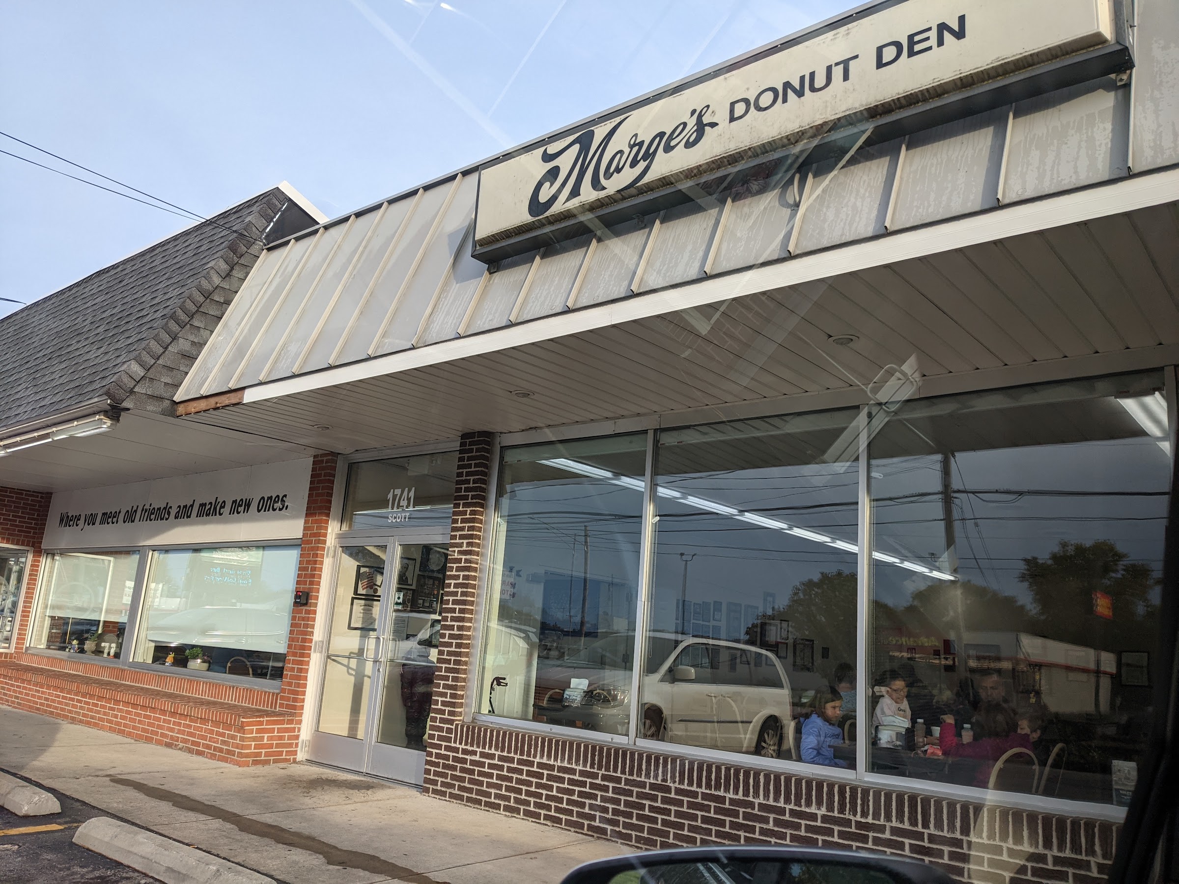 The Marge's Donut Den storefront on 28th Street with its channel sign and the window line 'Where you meet old friends and make new ones'